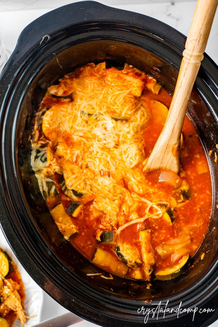 a crock pot filled with pasta and cheese on top of a white tablecloth