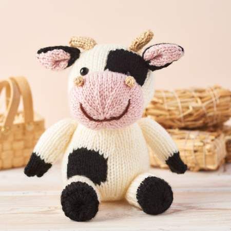 a stuffed cow sitting on top of a wooden table next to baskets and wicker baskets