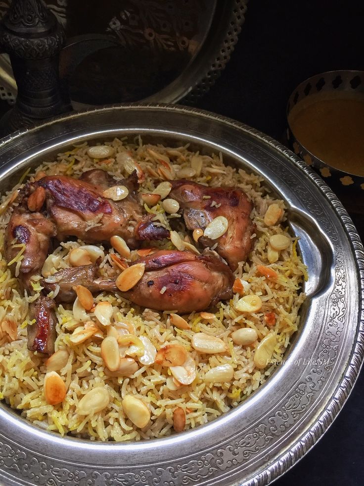 a silver plate topped with rice covered in meat and nuts