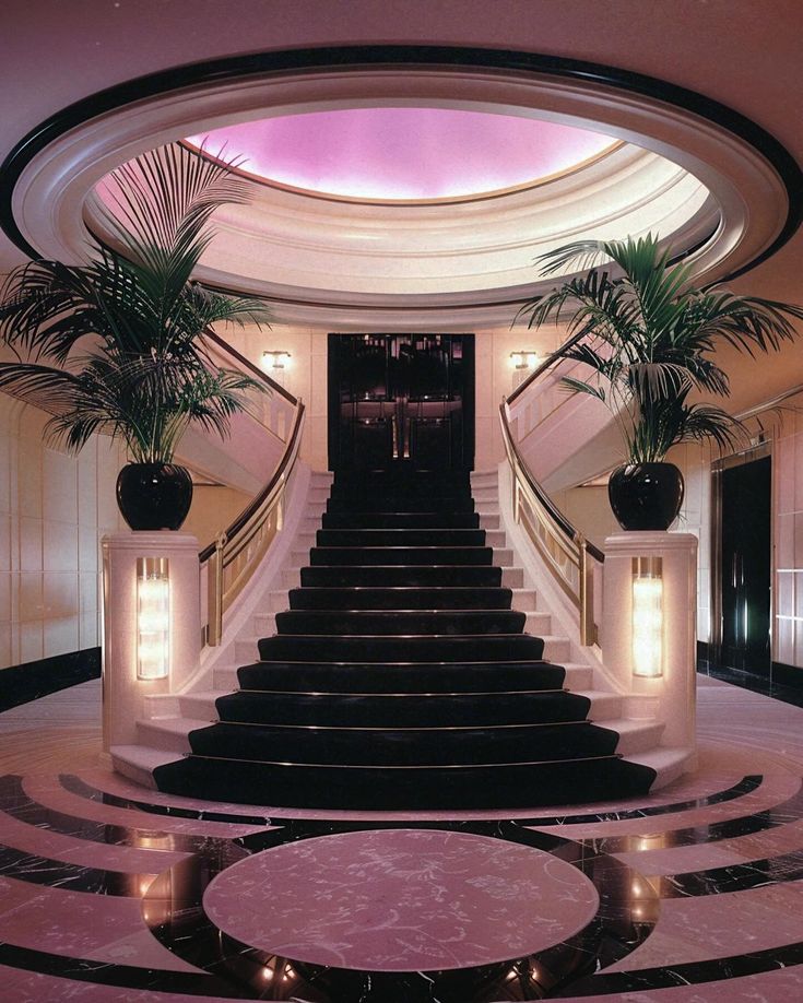 the stairs are lined with potted palm trees in front of an elegant entry way