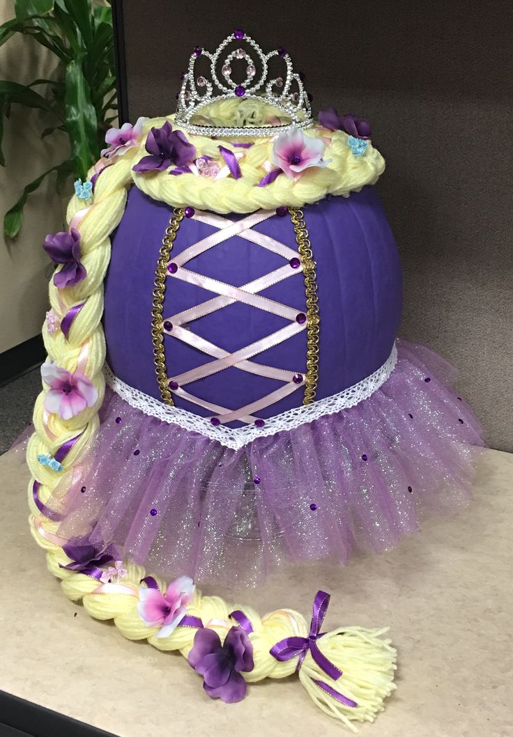 a purple pumpkin decorated with flowers and a tiara sitting on it's side