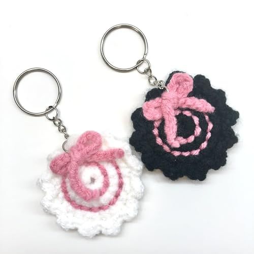 two crocheted keychains with pink and black designs on them, one is shaped like a flower