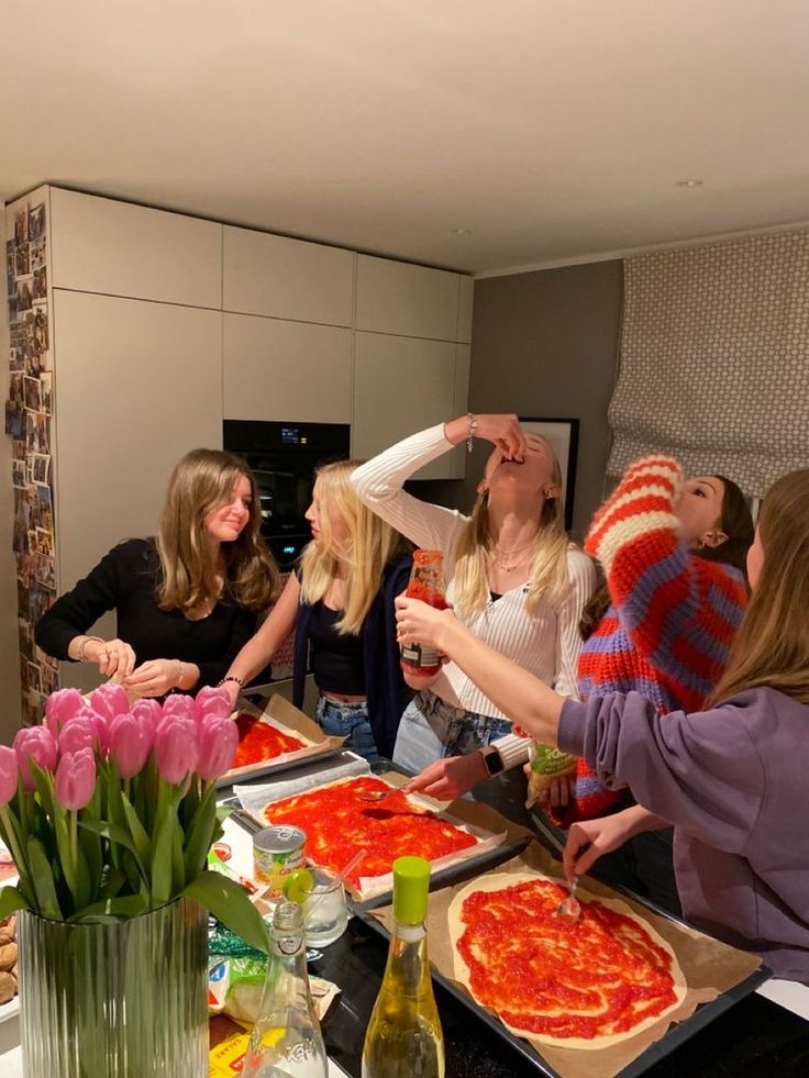 a group of women standing around a table with pizza