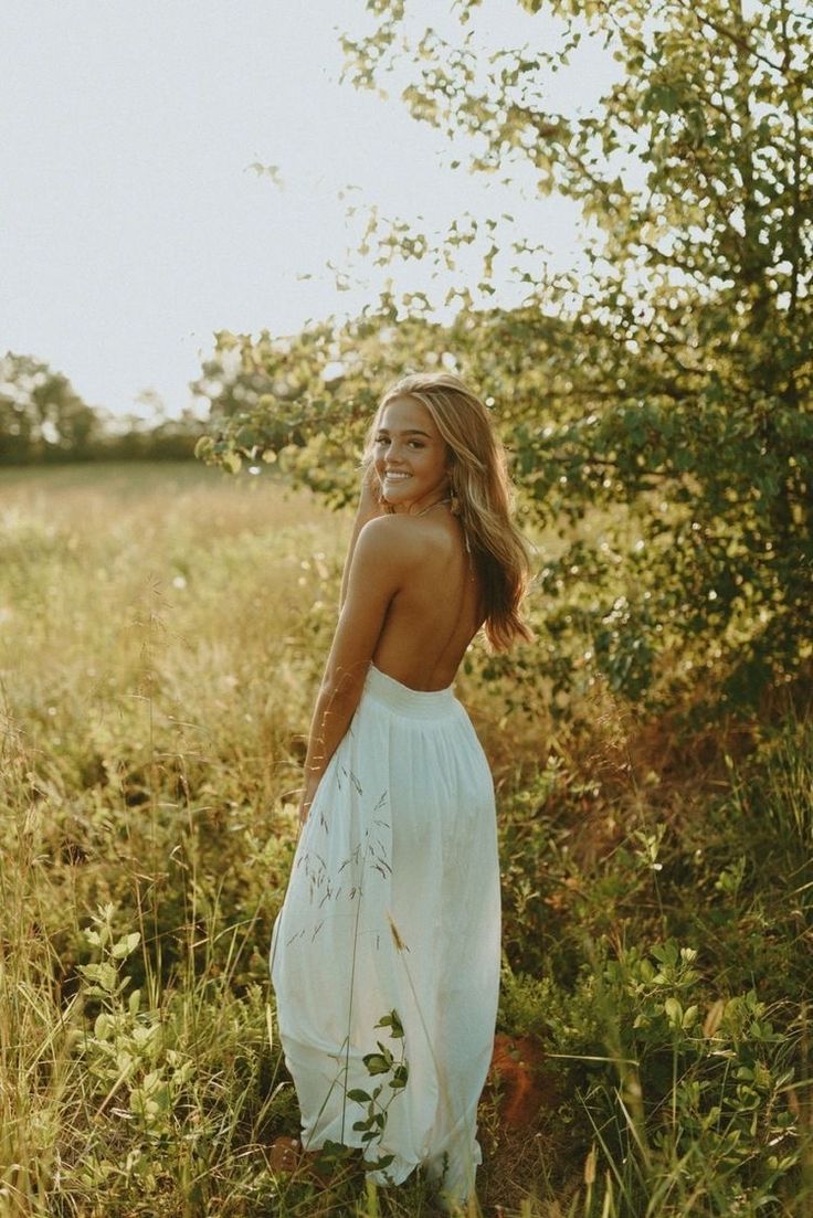 a woman in a white dress standing in tall grass