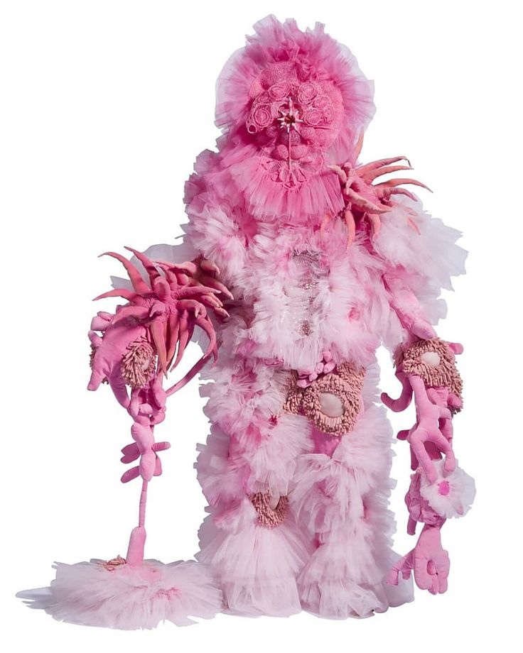 a stuffed animal is dressed in pink and white furs, with feathers on it's body