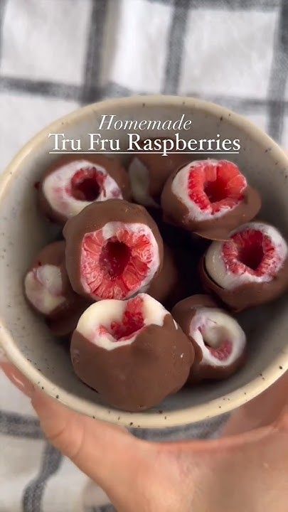 a person holding a bowl filled with chocolate covered fruit