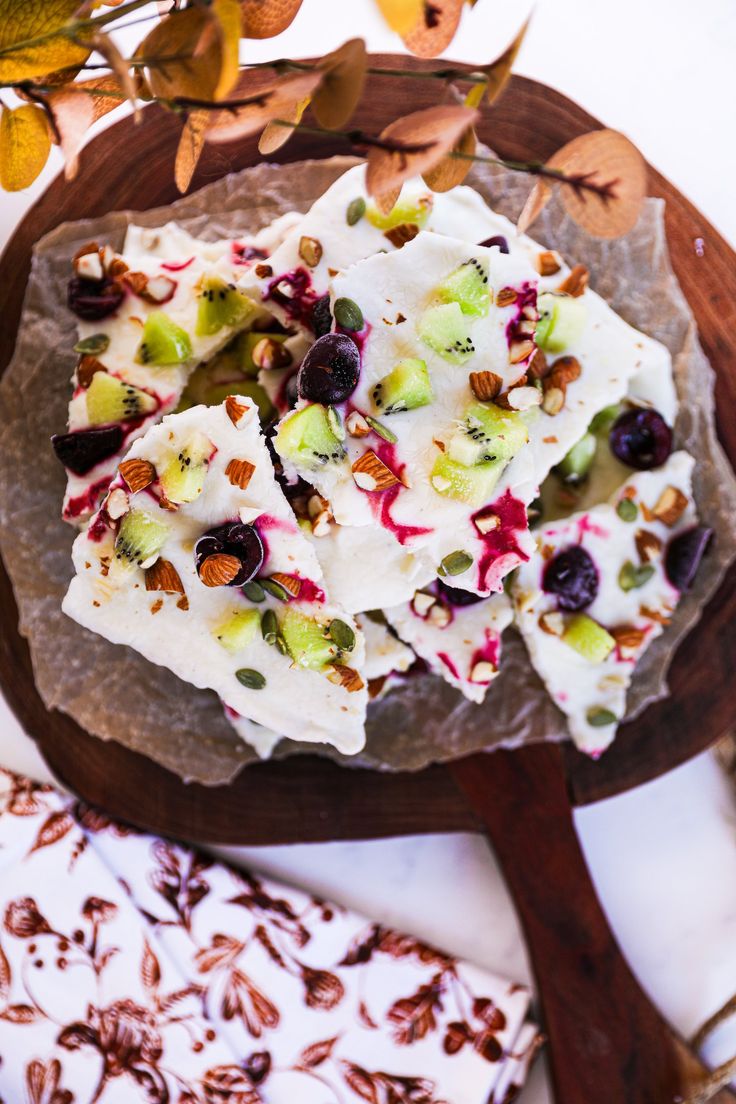 fruit and nuts arranged on top of a wooden platter next to other food items