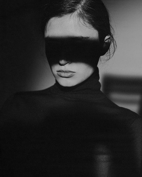 a woman with her face partially covered by the shadow of a blind folded over her eyes