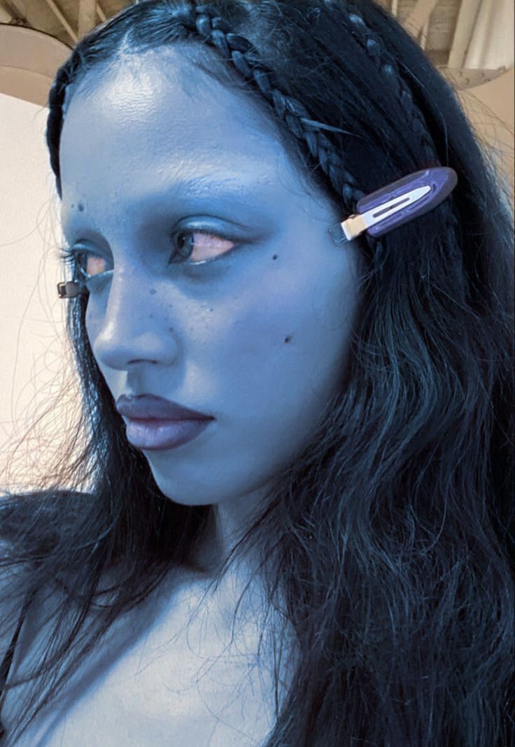 a woman with blue makeup is holding a hair brush