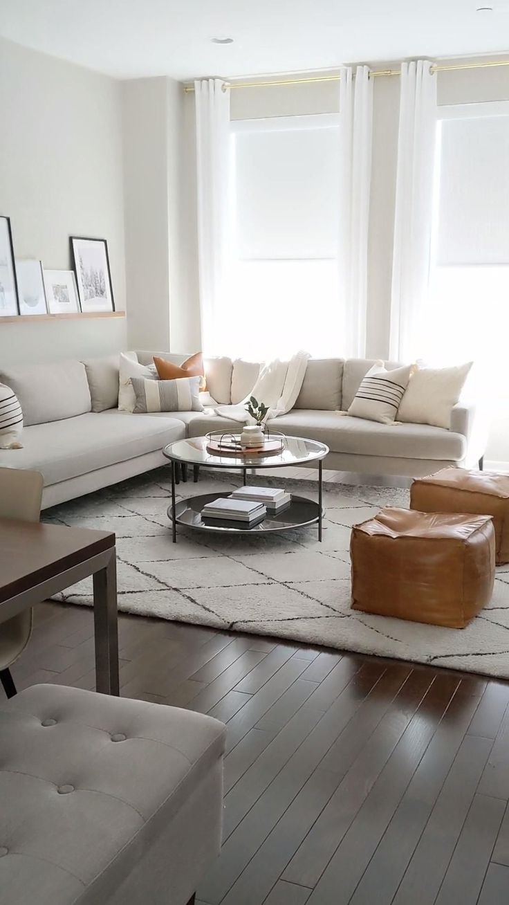 a living room filled with lots of furniture next to two large windows and white walls