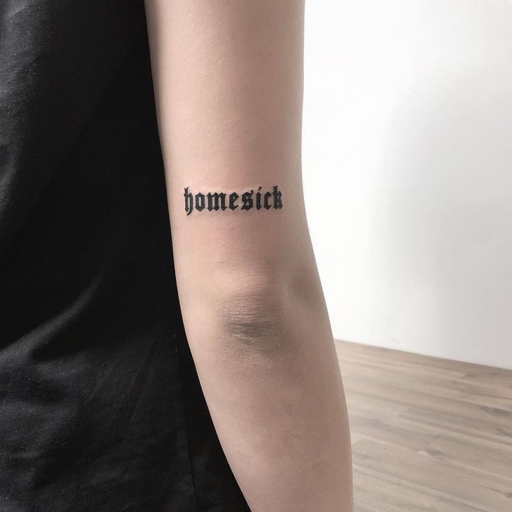 a woman's arm with the word homesick written on it in cursive font