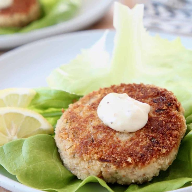 a crab cake is served with lettuce and lemon wedges on the side