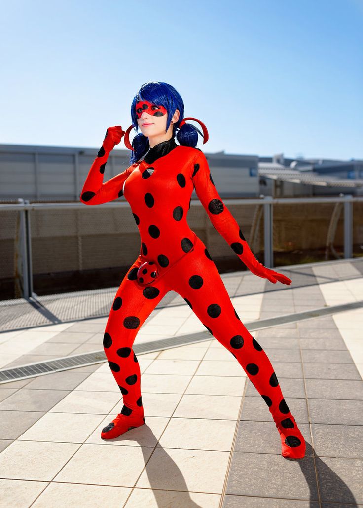 a woman in a red and black costume posing for the camera with her hands behind her head