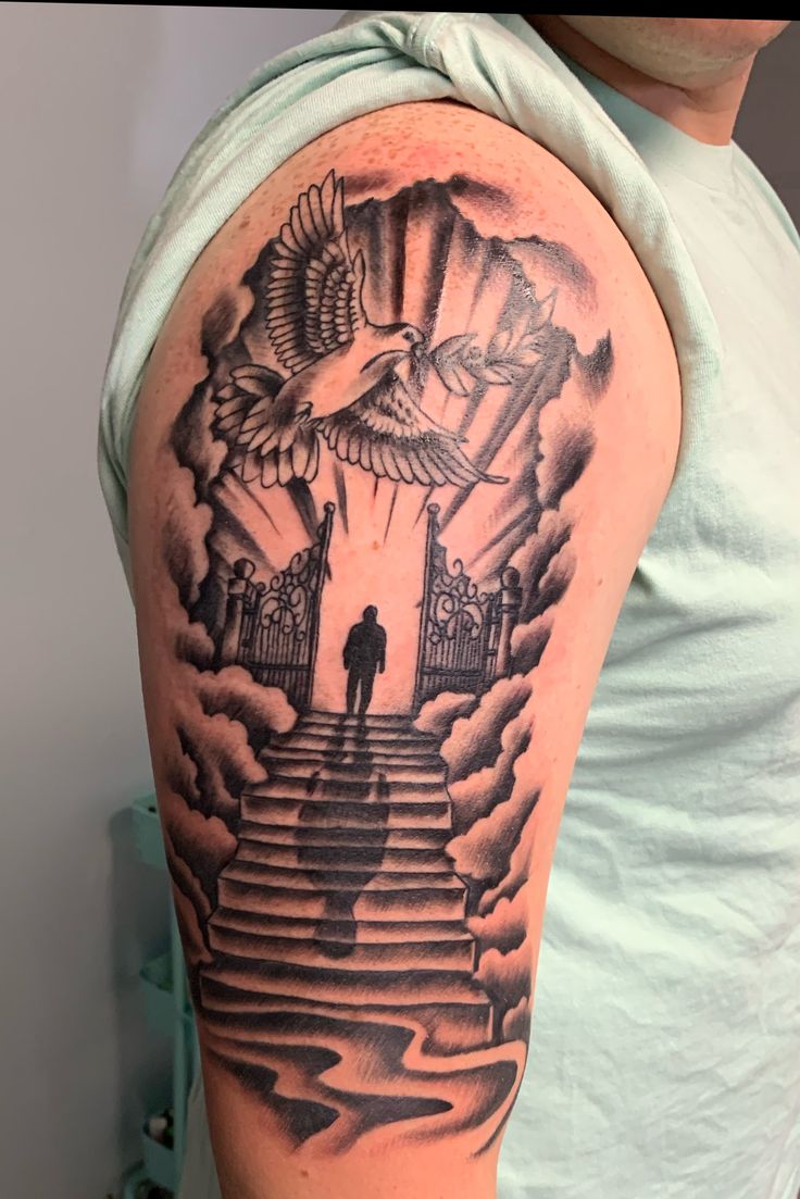 a man with a tattoo on his arm is standing in front of stairs and an eagle