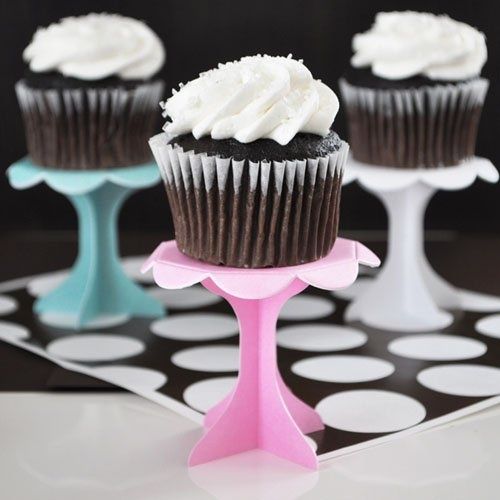 four cupcakes with white frosting sitting on top of each other in front of black and white polka dots