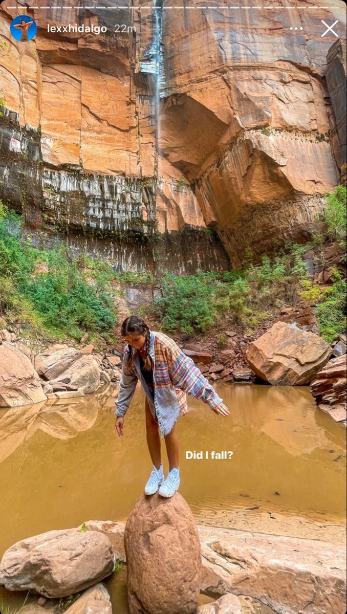 a woman standing on top of a rock next to a body of water in a canyon