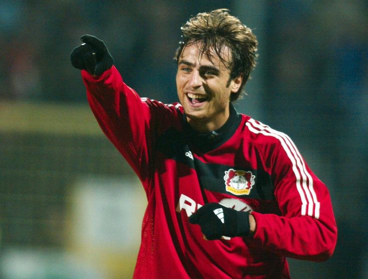 a soccer player with his arm in the air and pointing at something while wearing a red shirt