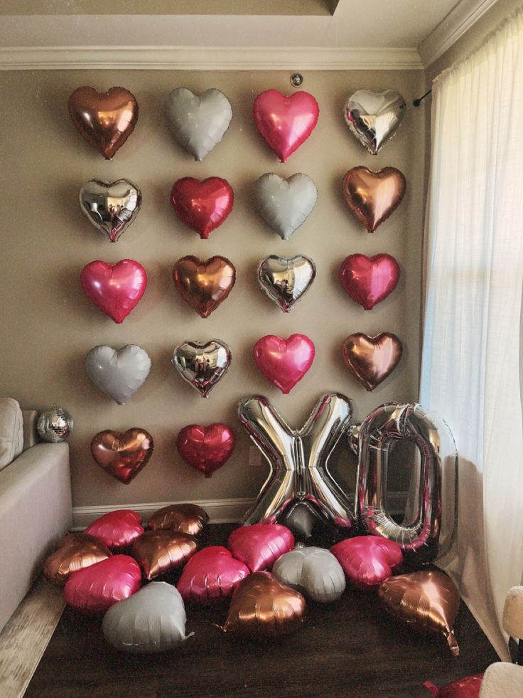 balloons are arranged on the floor in front of a wall decorated with letters and hearts