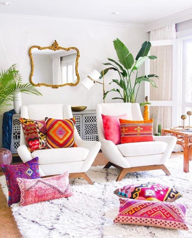 a living room filled with white furniture and lots of pillows on top of a rug