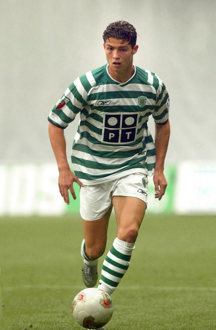 a soccer player in green and white uniform on the field with a ball near his feet