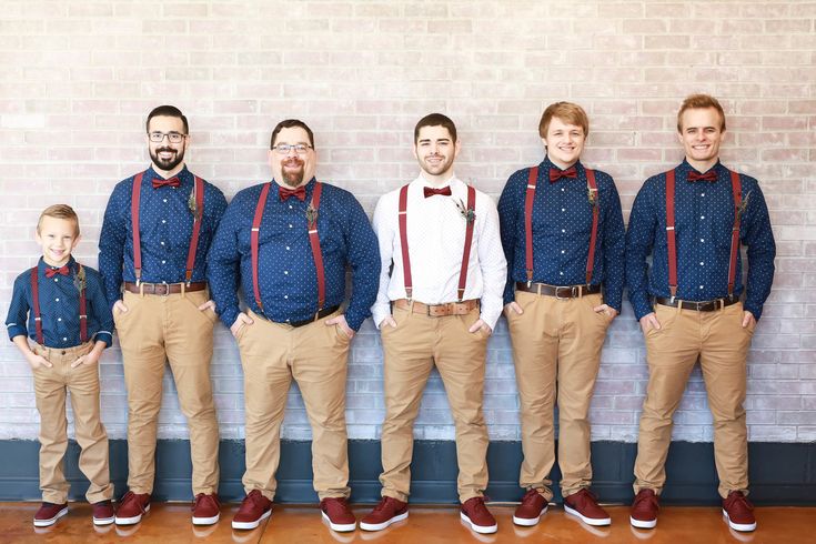 a group of men standing next to each other in front of a white brick wall