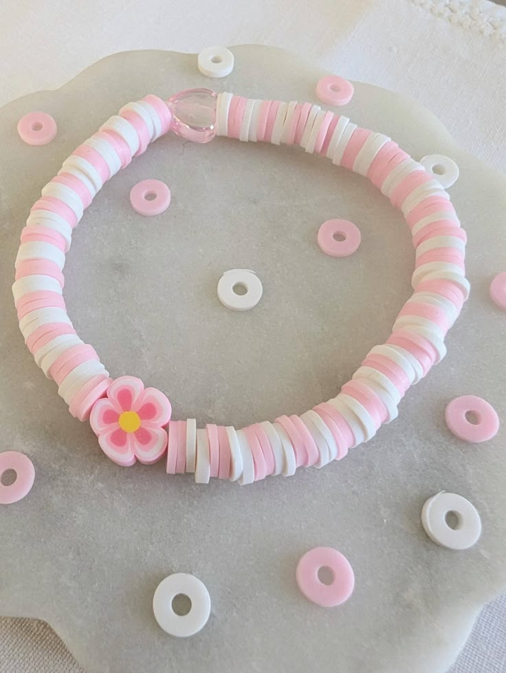 a pink and white bracelet sitting on top of a table next to doughnuts