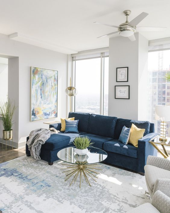 a living room with blue couches and yellow pillows on top of the rugs