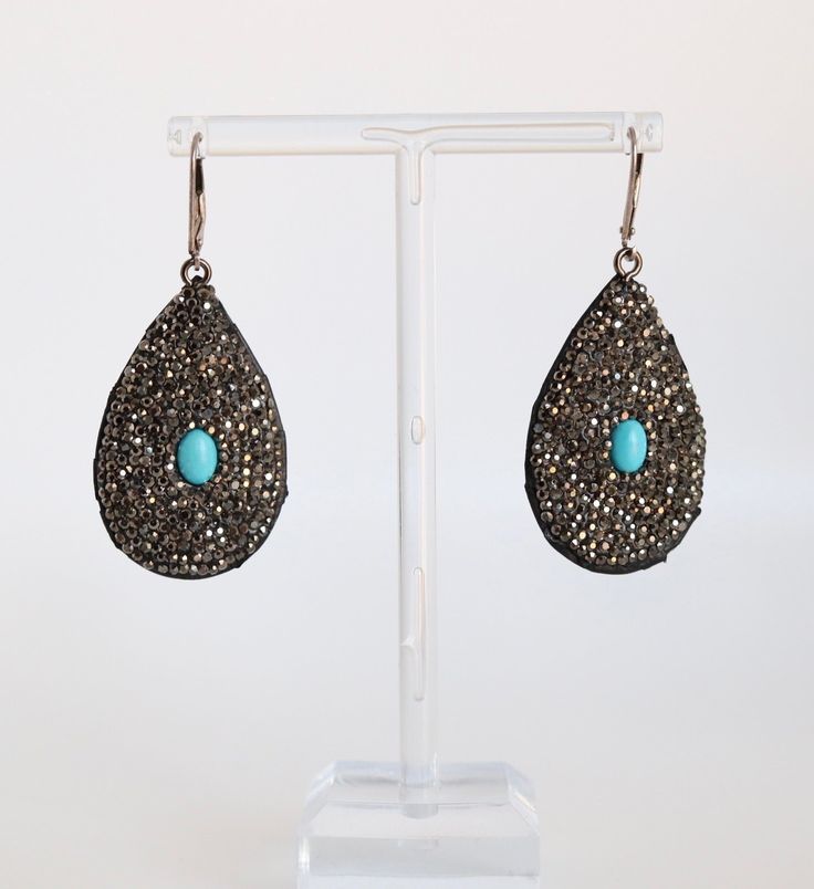 Enhance your jewelry collection with the exquisite Black Rhinestones Paved Turquoise Earrings. These stunning earrings feature a paving of black rhinestones and a vibrant turquoise gem, creating a unique and eye-catching look. Elevate any outfit with these elegant and expertly crafted earrings. Turquoise Earrings For Evening, Turquoise Jewelry For Party, Elegant Turquoise Jewelry With Rhinestones, Black And Turquoise Beaded Earrings, Turquoise And Black Earrings, Southwestern Black Beaded Dangle Earrings, Peacock-colored Bohemian Earrings For Gift, Turquoise Gem, Crafted Earrings