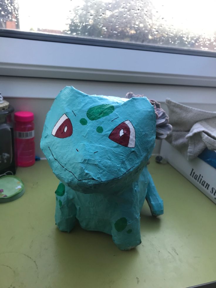 a blue paper mache sitting on top of a green table next to a window