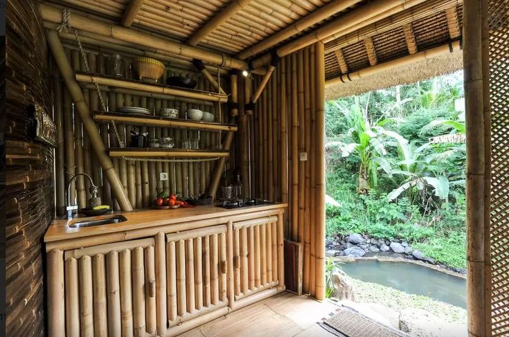 a kitchen with bamboo walls and flooring in front of a sliding glass door that leads out to the jungle