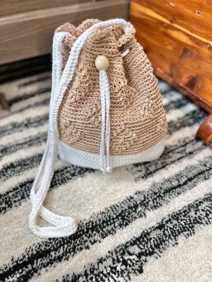 a crocheted bag sitting on top of a rug next to a wooden box