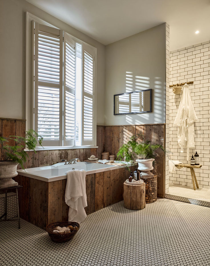 a bath room with a large tub and a sink next to a window filled with potted plants