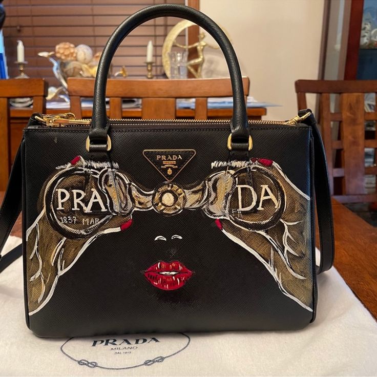 Hand Painted By An Artist Gorgeous Prada Bag Excellent Condition- It’s Exclusive Peace Worn Only Few Times Designer Saffiano Leather Shoulder Bag, Designer Black Saffiano Leather Shoulder Bag, Black Luxury Saffiano Leather Shoulder Bag, Luxury Black Saffiano Leather Shoulder Bag, Designer Saffiano Leather Shoulder Bag With Handles, Black Saffiano Leather Shopping Bags, Designer Gold Saffiano Leather Shoulder Bag, Designer Saffiano Leather Evening Bag, Prada Nylon Tote Bag