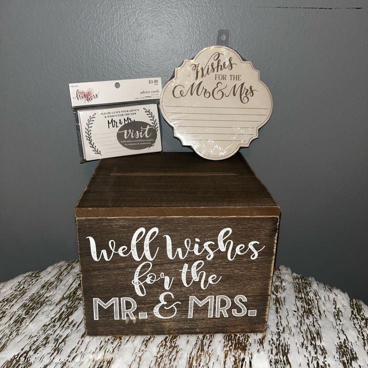 a wooden box sitting on top of a bed with a sign that says well wishes for the mr and mrs