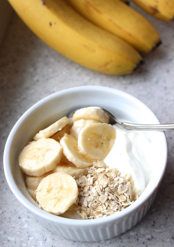 a bowl filled with oatmeal and bananas on top of a table next to two bananas