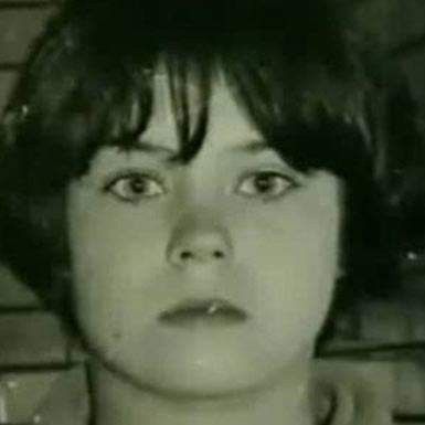 an old black and white photo of a woman with short hair looking at the camera