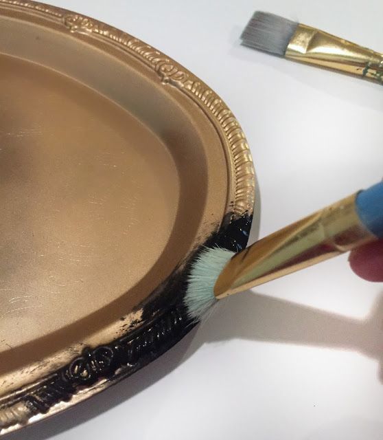 a person holding a paintbrush near a gold plate