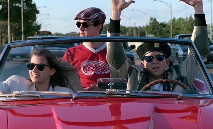 two people sitting in a convertible car with their hands up and one person wearing sunglasses