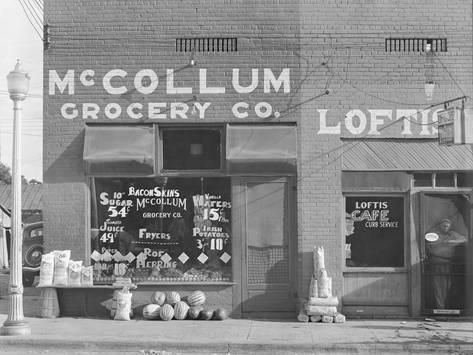 an old black and white photo of a grocery store with lots of signs on the front