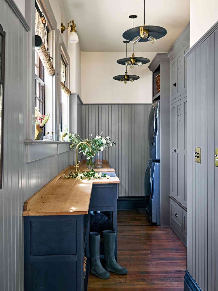 a long narrow kitchen with wooden counter tops and blue cabinets, along with hanging lights