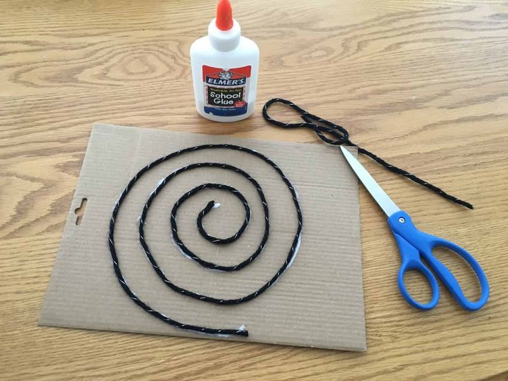 a pair of scissors and glue sitting on top of a piece of paper next to a string