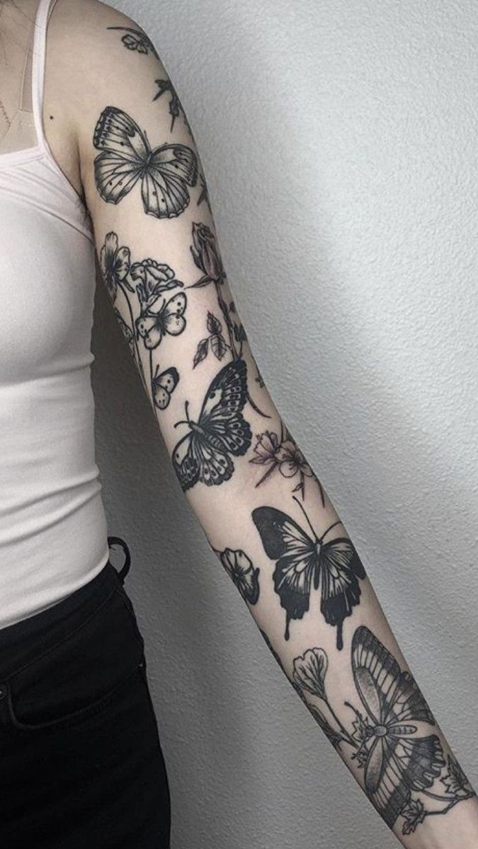 a woman's arm with butterflies on it and a white wall in the background