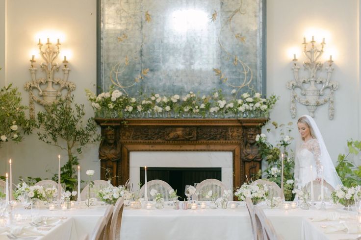 a bride and groom sitting at a table in front of a fireplace with candles on it