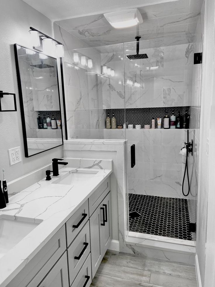 a white bathroom with two sinks and a shower stall in the corner, all decorated in black and white marble