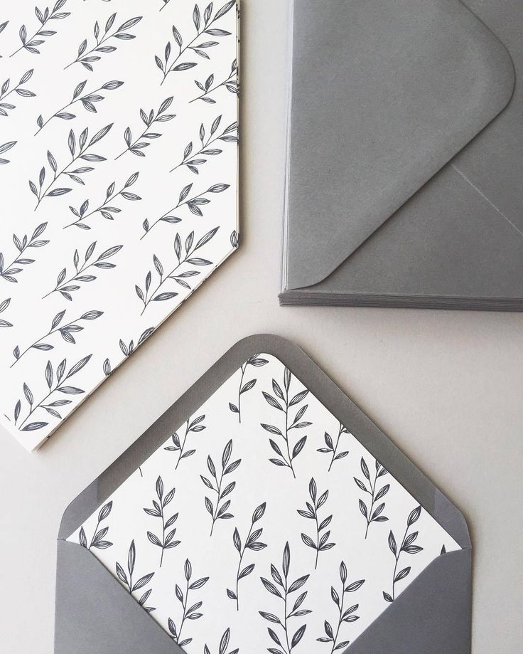 two envelopes with black and white leaves on them next to an envelope that is open