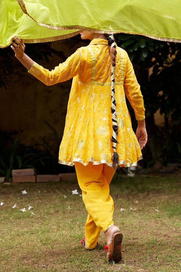 Turmeric yellow short umbrella cut collared kurta in pure chanderi base with mukaish bloom embroidery and golden lumpi lace detailing on neck and hemline. Paired with dhoti pant and lime green fringe border chiffon dupatta.
Components: 3
Pattern: Embroidery
Type Of Work: Mukaish
Neckline: Collar
Sleeve Type: Three Fourth
Fabric: Pure Chanderi, Chiffon
Color: Yellow
Other Details: 
Attached inner lining
Weight: 800gms
Length:
Kurta: 33inches
Sleeves: 22inches
Dhoti pant: 44inches
Model Height: 5f Bloom Embroidery, Turmeric Yellow, Dhoti Pants, Yellow Short, Chiffon Dupatta, Pattern Embroidery, Yellow Shorts, Pant Set, Set For Women