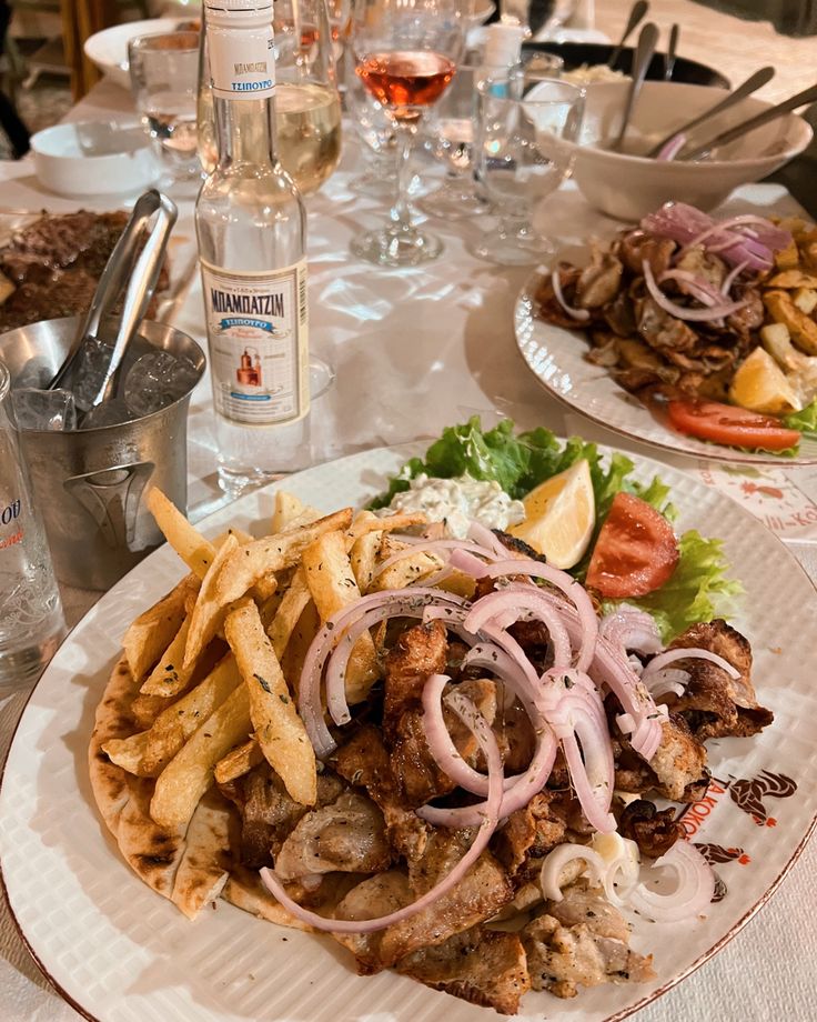 two plates with food on them sitting on a table next to wine glasses and water bottles