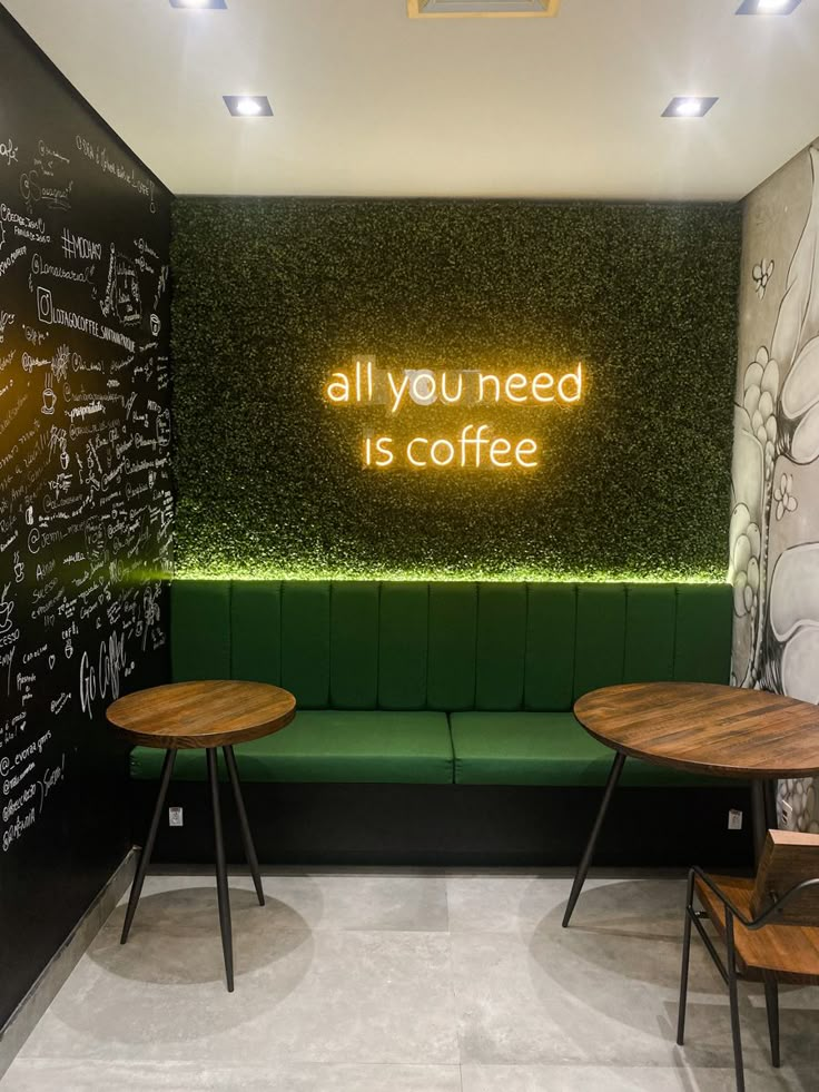 two wooden tables sitting in front of a green bench with writing on the wall behind it