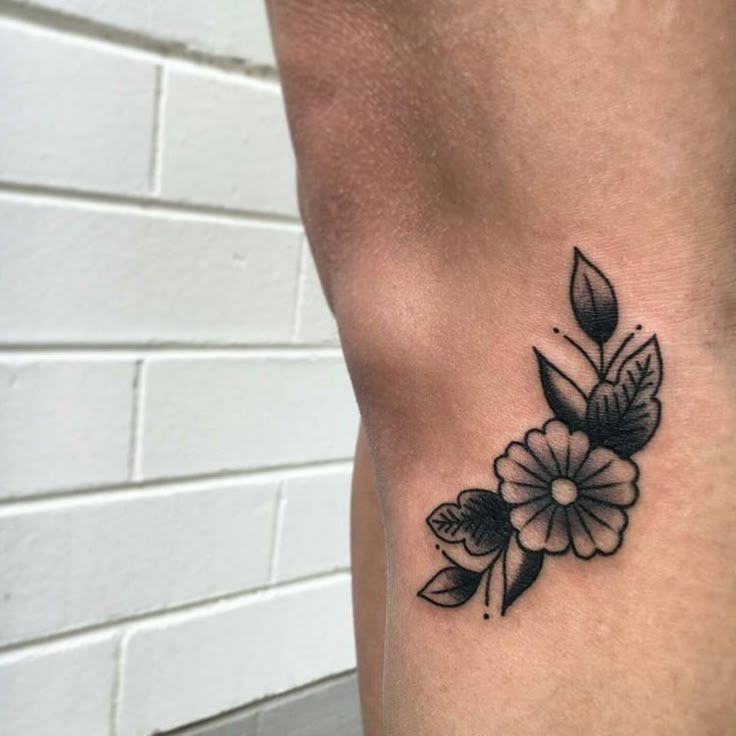 a black and white flower tattoo on the side of a woman's right leg