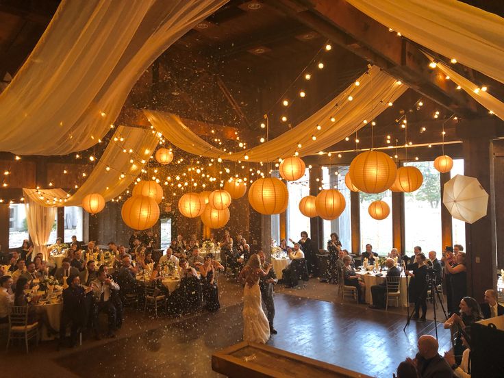 a wedding reception with paper lanterns hanging from the ceiling